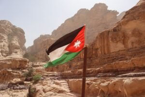 Explore the striking rock formations and Jordanian flag in Wadi Musa, Ma'an Governorate, Jordan.