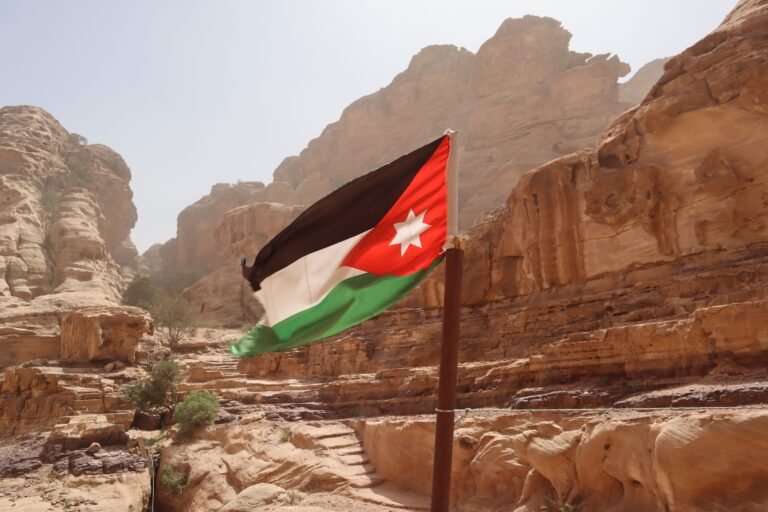 Explore the striking rock formations and Jordanian flag in Wadi Musa, Ma'an Governorate, Jordan.